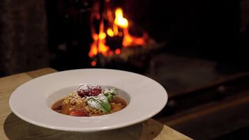 A white plate with a dessert on a wooden table, with a fireplace in the background.