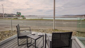 An outdoor seating area with a view of a lake and distant mountains.