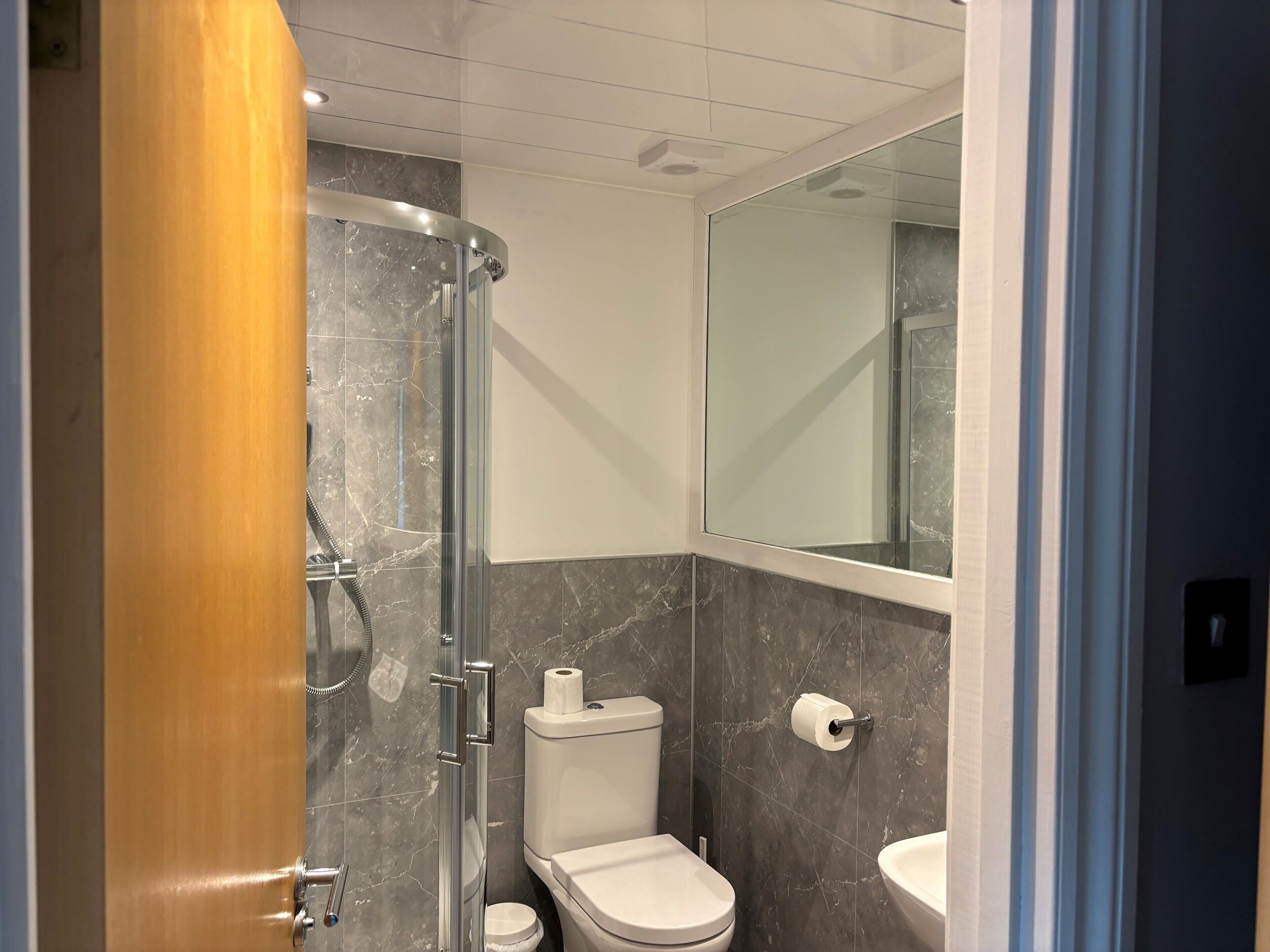 A modern bathroom with a glass shower enclosure, a toilet, and a sink.