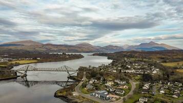 A bridge over a river with a town in the foreground and mountains in the background.