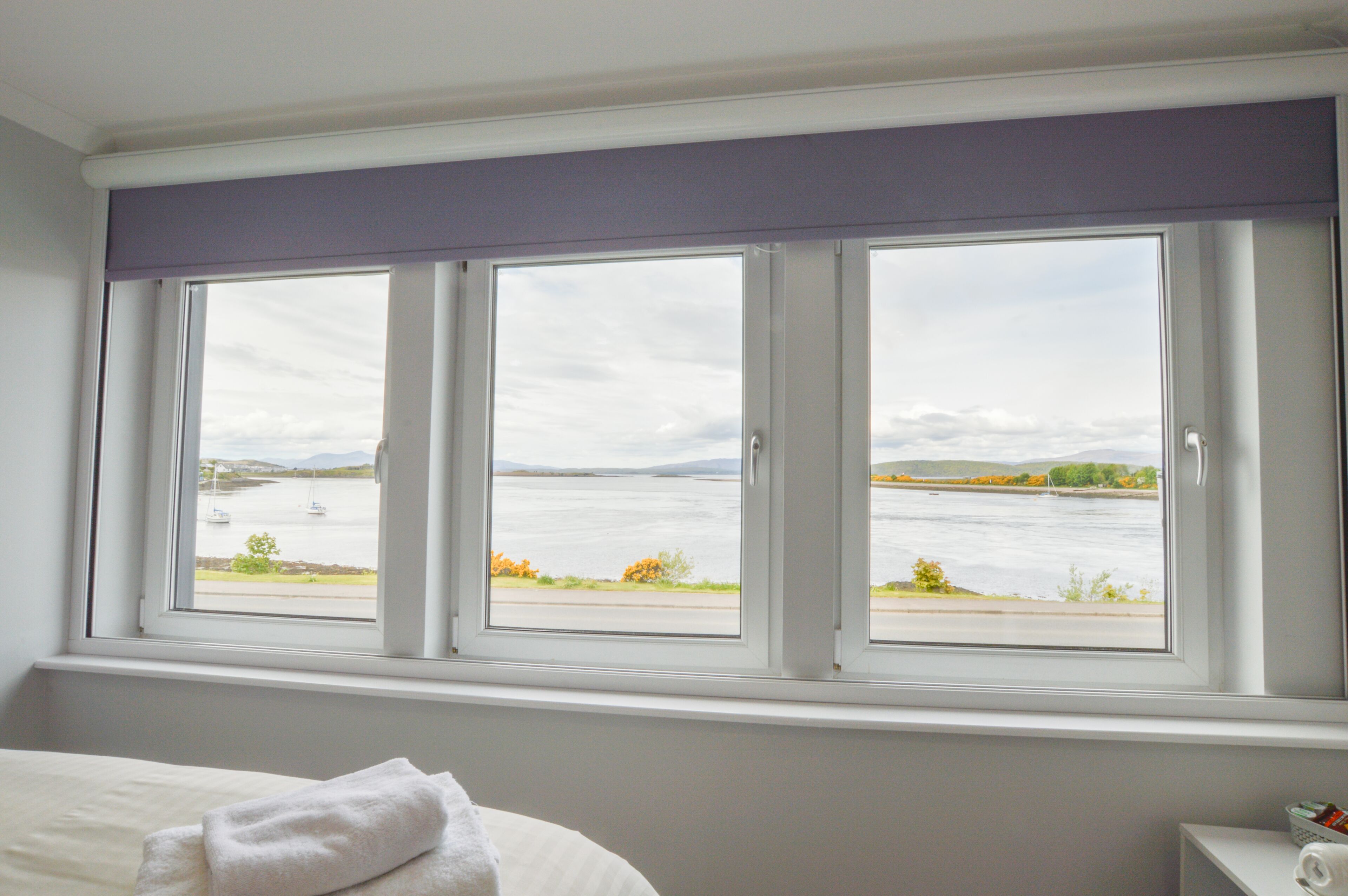 A hotel room with a large window overlooking a body of water and a distant shoreline.