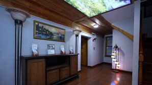 Un pasillo con suelo de madera, un armario de madera con marcos de fotos, un techo con tragaluz y una escalera.