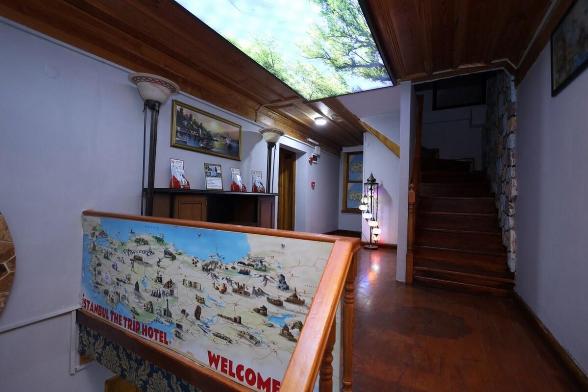 A lobby with a wooden staircase, a map display, and a reception area.