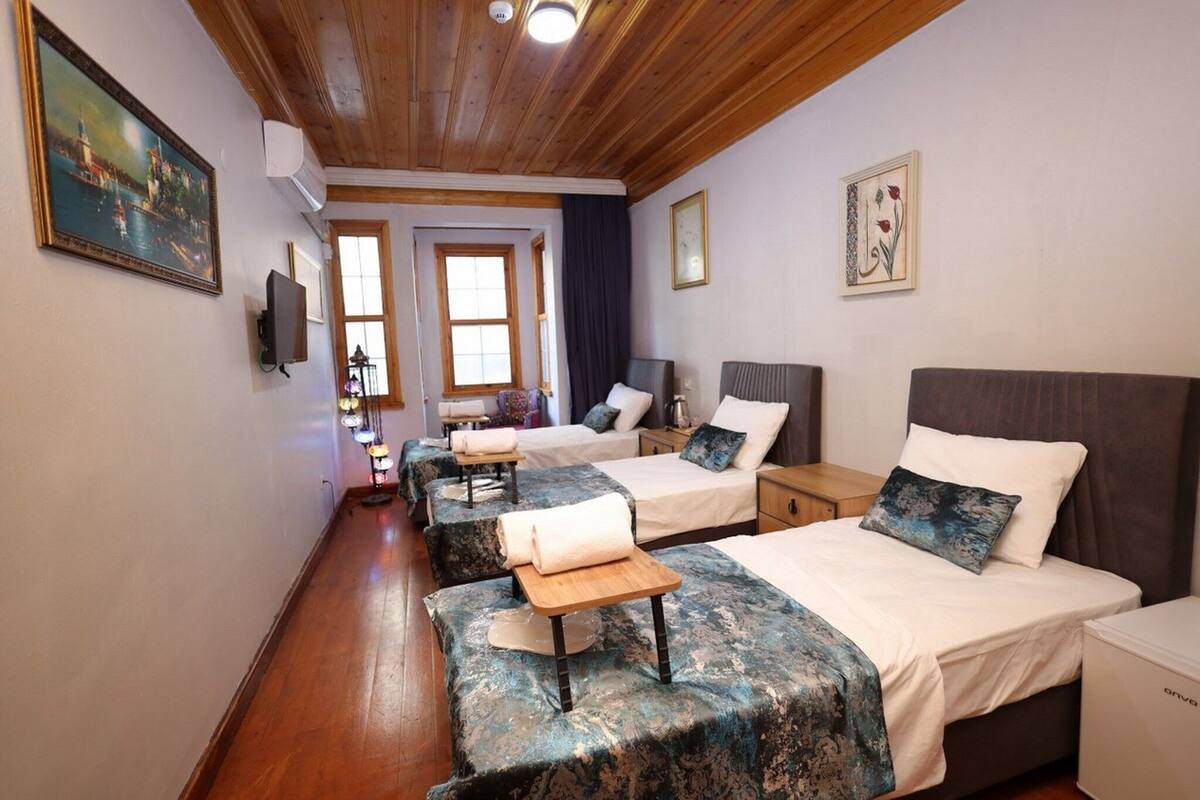 A hotel room with two beds, a wooden ceiling, and a painting on the wall.