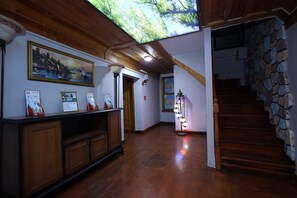 Ein Flur mit Holzdielen, einer Steintreppe und einer Decke mit Oberlicht.