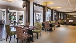 A spacious dining area with multiple tables and chairs, large windows, and hanging pendant lights. - Sabai Sabai Sukhothai (Sawankhalok)
