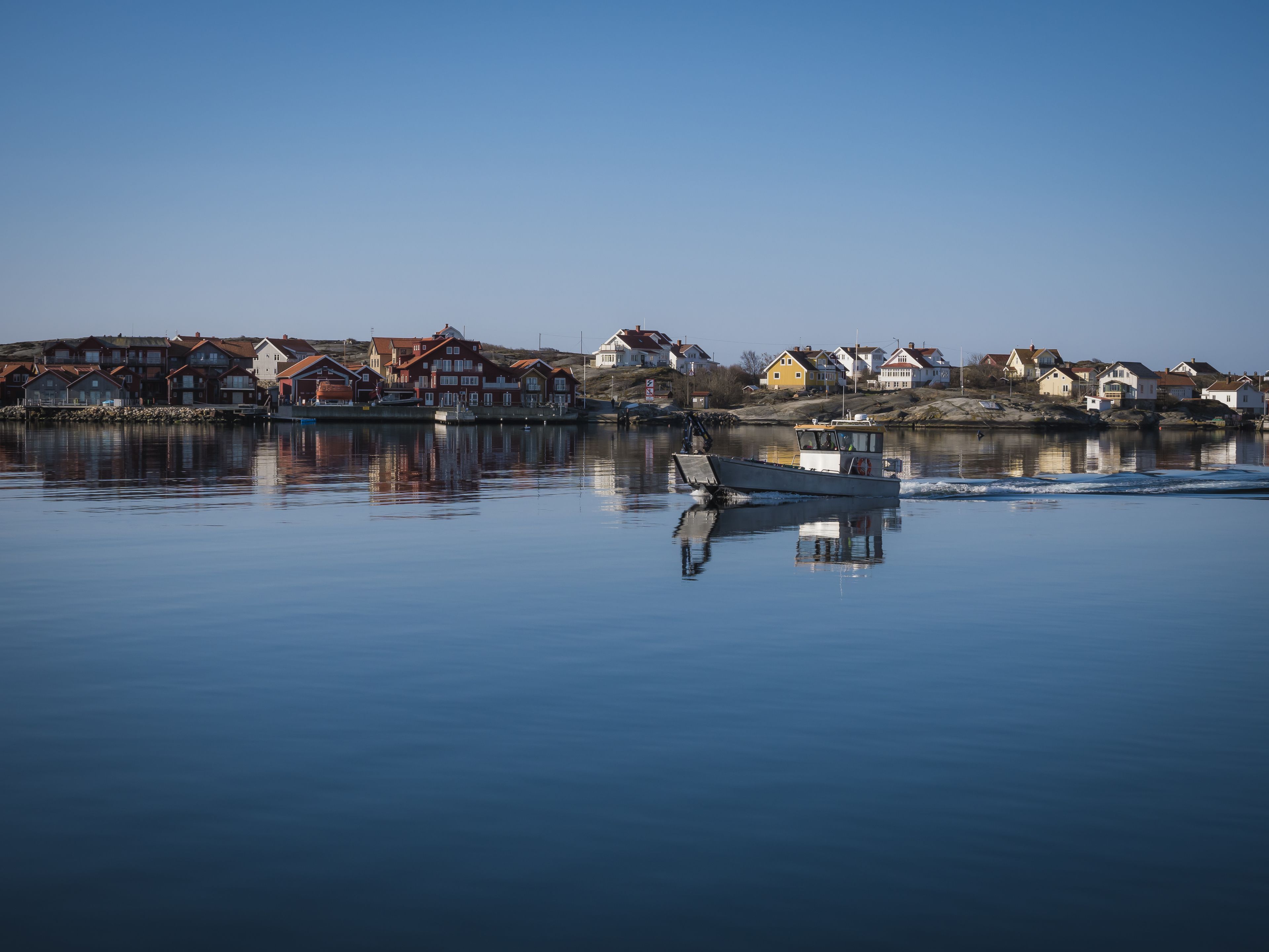 A calm waterfront with a row of houses and a small boat.