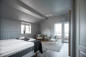Un dormitorio con cama, ventana, una silla y vistas al exterior.