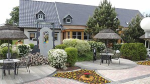 A courtyard with outdoor seating, a stone wall, and a building with a grey tiled roof. - Haffblick (1) - Landhaus Mönkebude (Mönkebude)