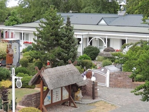 A traditional building with a thatched-roof structure, surrounded by well-maintained gardens and a white fence. - Haffblick (1) - Landhaus Mönkebude (Mönkebude)