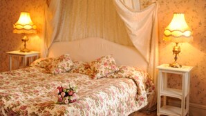 Una cama con ropa de cama floral, un dosel y dos lámparas de noche.