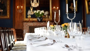 Mesa formal para comedor dispuesta con mantel blanco, cubertería y cristalería.