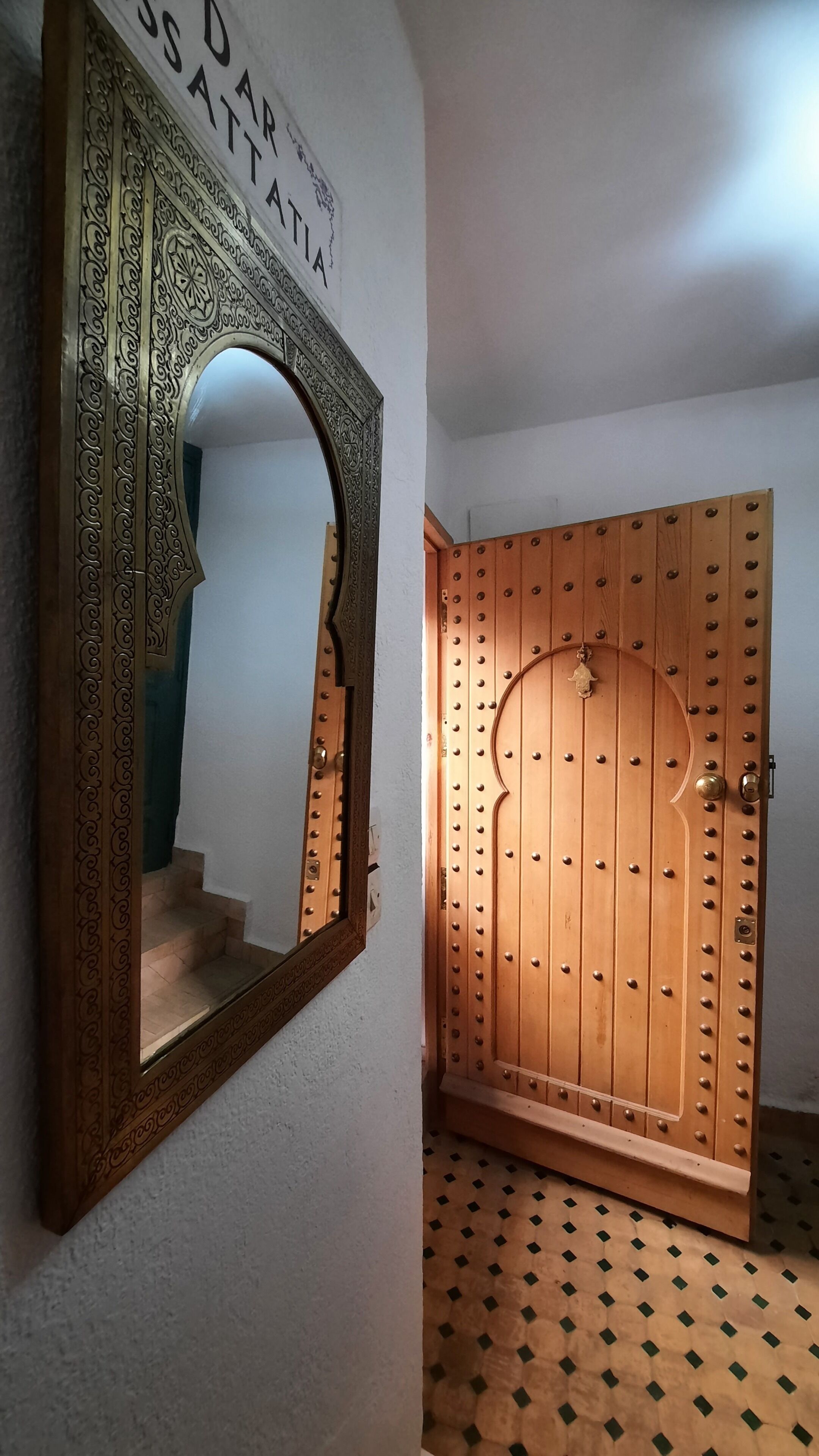 A hallway with a wooden door featuring a decorative metal frame and a sign above it.