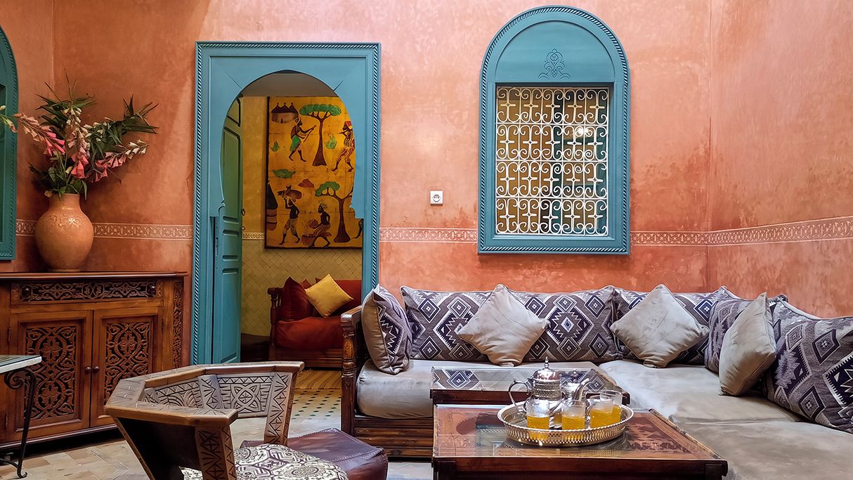 Una sala de estar en estilo marroquí con un sofá, una mesa de centro con una bandeja y una pared con un biombo decorativo.