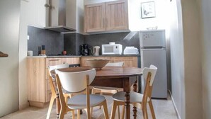A kitchen with wooden cabinets, a dining table with chairs, a microwave, a coffee maker, and a refrigerator. - House with pool and river access (Fontaine-de-Vaucluse)