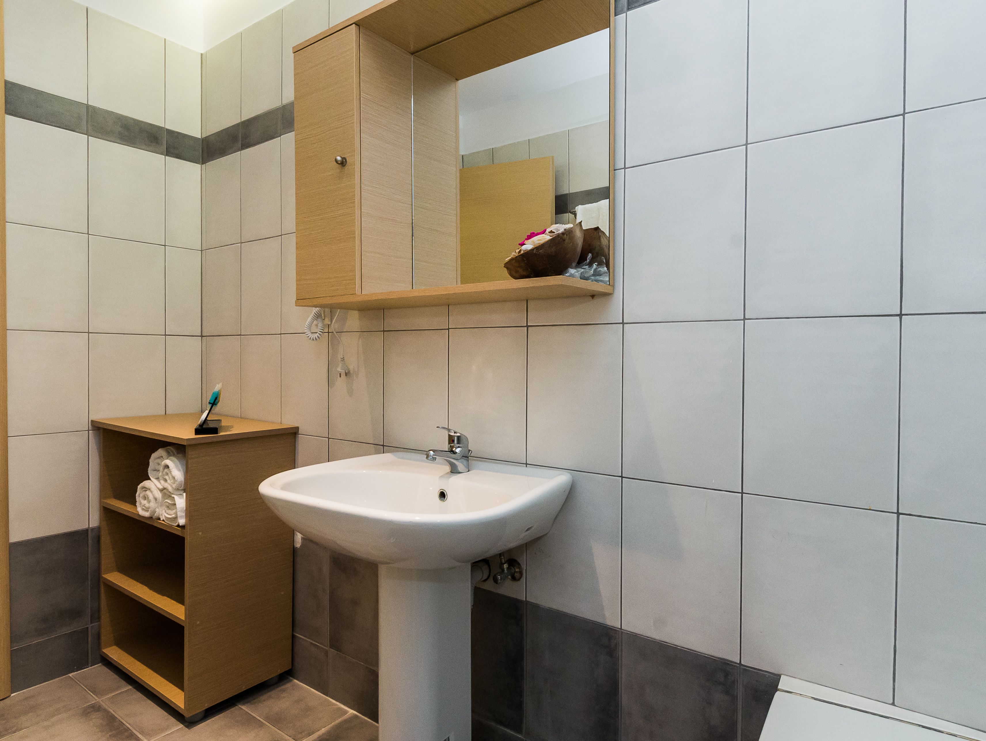 A bathroom with a sink, mirror, and wooden shelves with towels.