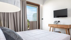 A hotel room with a large bed, a desk with a flat-screen TV, and a window with curtains. - Alektor Studios & Apartments (Zakynthos)