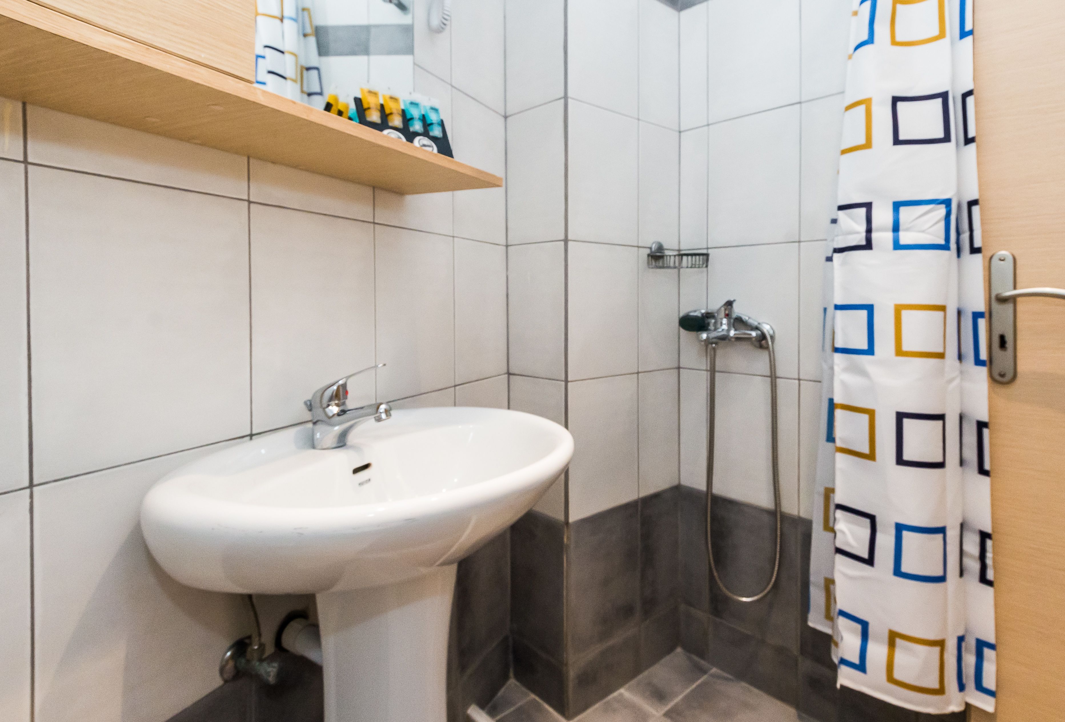 A bathroom with a white sink, a shower, and a towel rack.