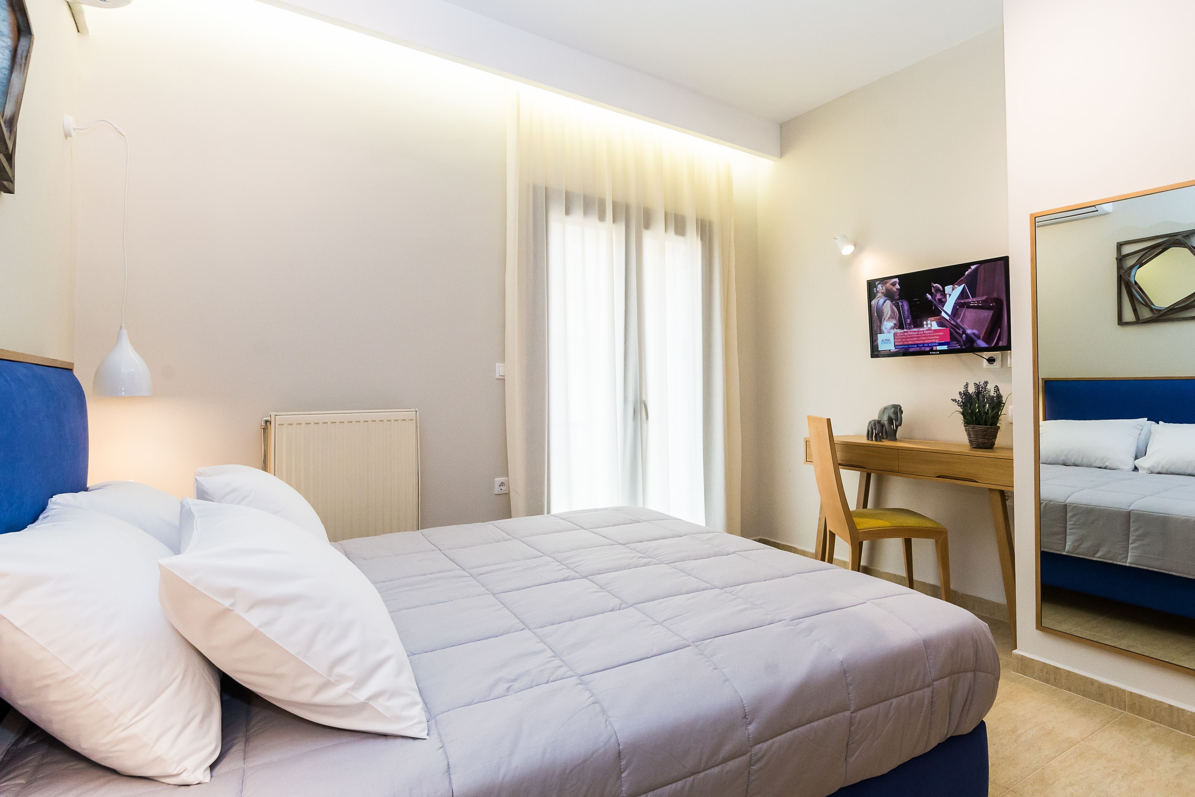 Een hotelkamer met een bed, een bureau, een stoel, een televisie en een spiegel.