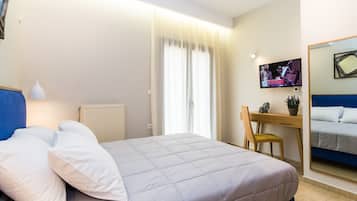 Habitación de hotel con cama, escritorio, silla, televisor y espejo.