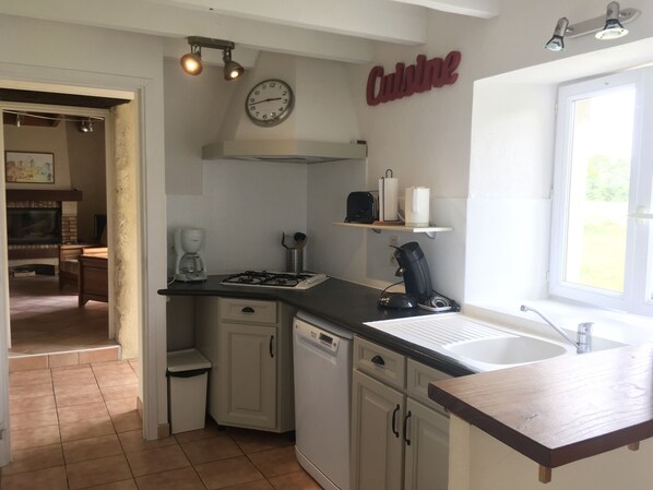 A compact kitchen with a stove, coffee maker, and a clock on the wall.