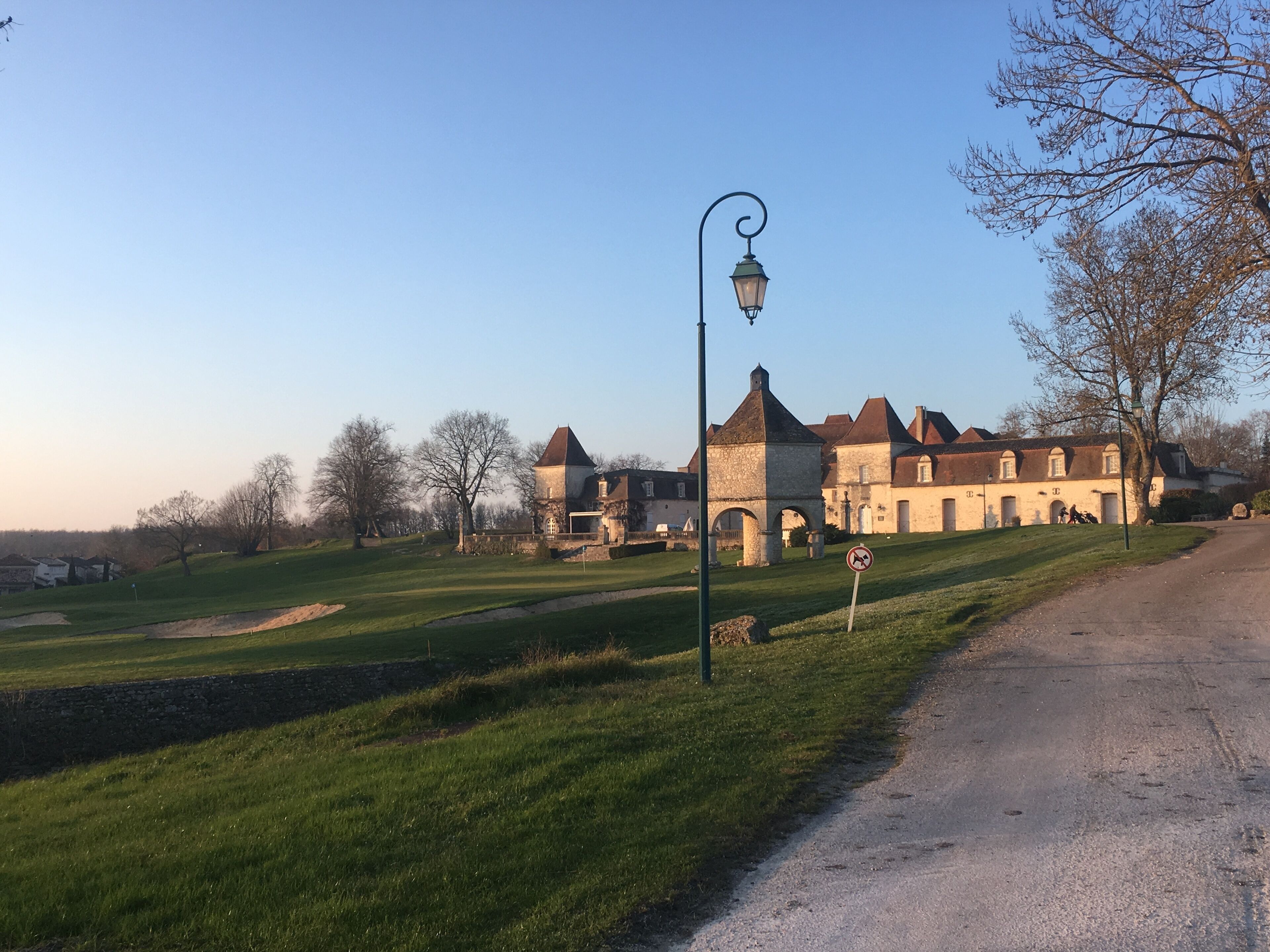 A historic building with multiple towers and a paved road alongside.