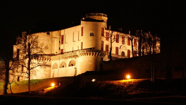 A historic building with a round tower, arched windows, and a balcony.