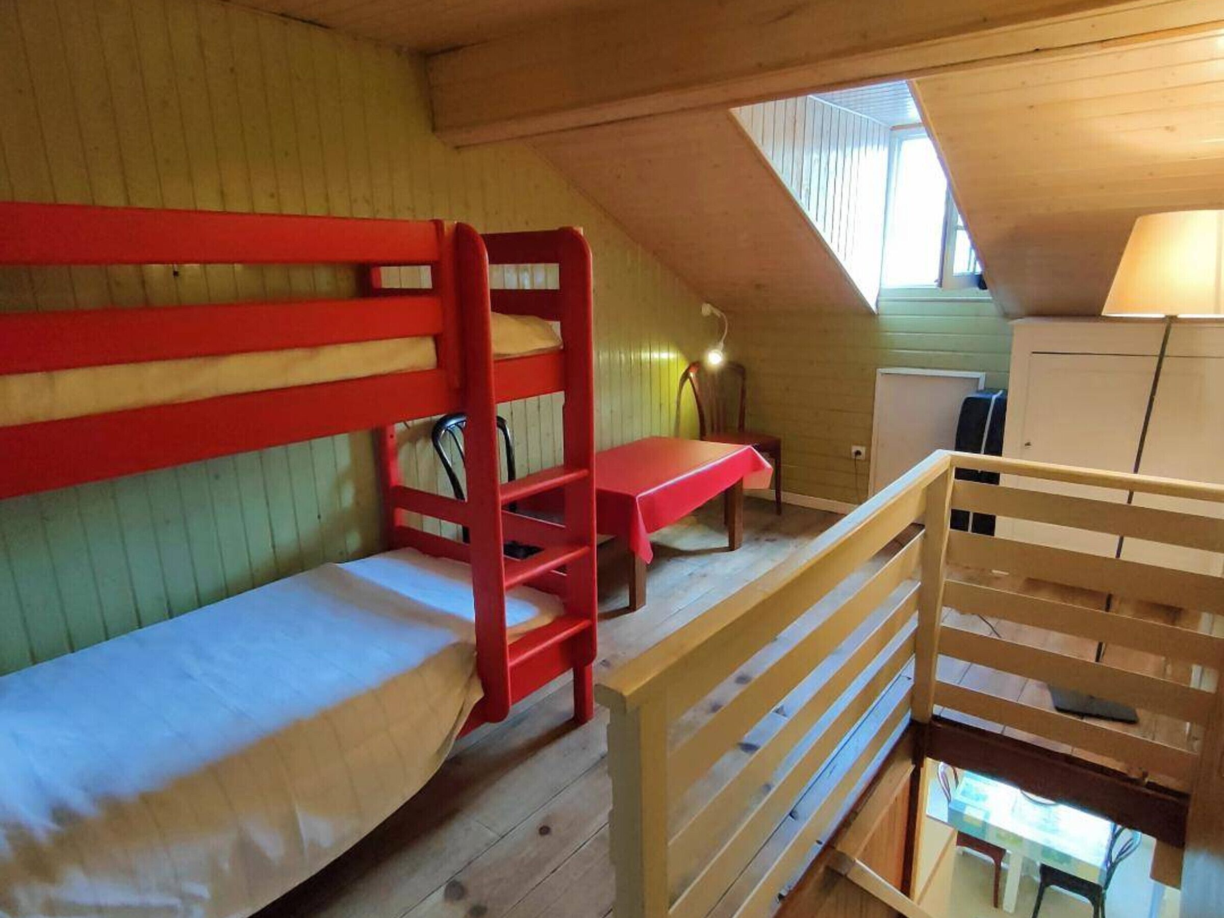 Une chambre de dortoir équipée de lits superposés, d’un bureau, d’une chaise et d’une petite kitchenette.