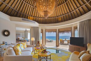 A spacious living area with a large chandelier, a pool, and a view of the ocean. - The Nautilus Maldives (Thiladhoo)