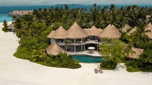 Un resort con villas de techo de paja, piscina y playa.