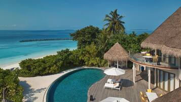 Un resort con piscina, sillas de descanso y vista al océano.
