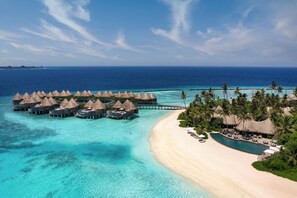 An overwater bungalows with thatched roofs, a beach, and a clear blue sea. - The Nautilus Maldives (Thiladhoo)