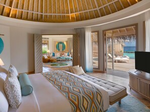 A spacious room with a large bed, a TV, and a view of the ocean through a sliding glass door. - The Nautilus Maldives (Thiladhoo)