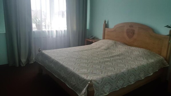A bedroom with a bed, curtains, a nightstand, and a wall with a crest emblem.