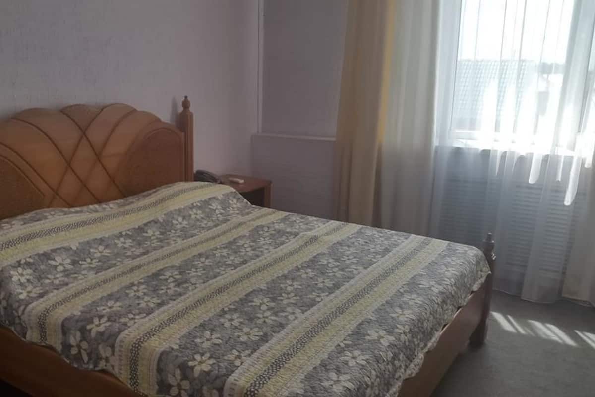 A bedroom with a wooden bed, a nightstand, and a bedside table.