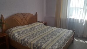A bedroom with a wooden bed, a nightstand, and a bedside table.