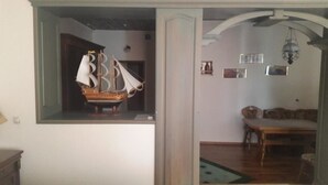 A room with a wooden table, a chair, and a hanging sailboat decoration. - Sapsan (Pavlodar)