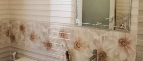 A bathroom with a marble sink, a toilet, and a mirror above the sink.