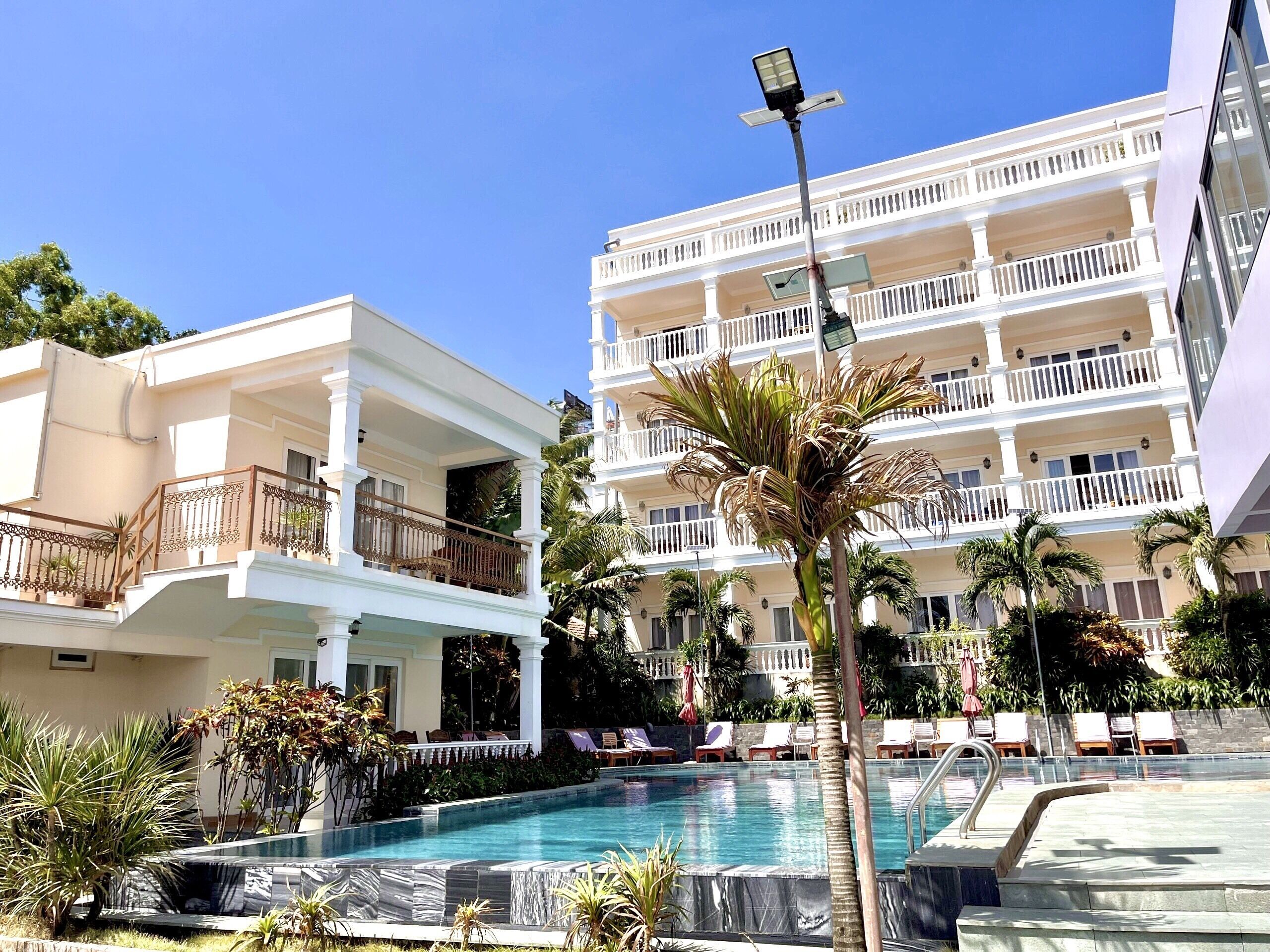 A hotel with a swimming pool, multiple balconies, and outdoor seating areas.