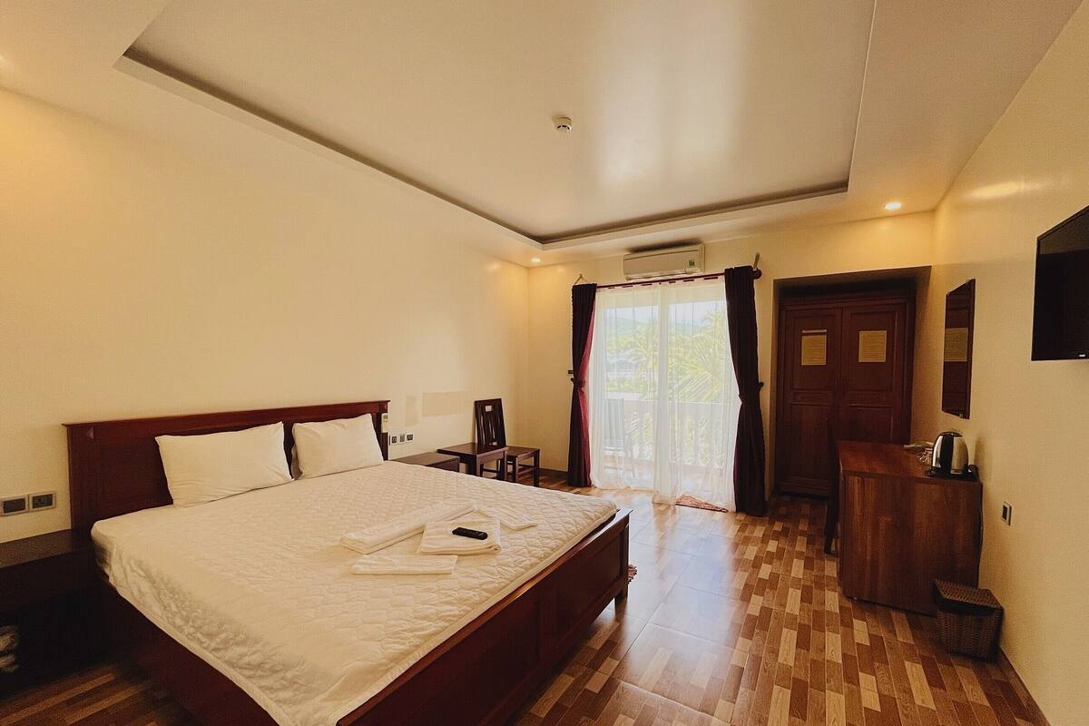 Habitación de hotel con una cama grande, un escritorio, una silla, un armario y un televisor.