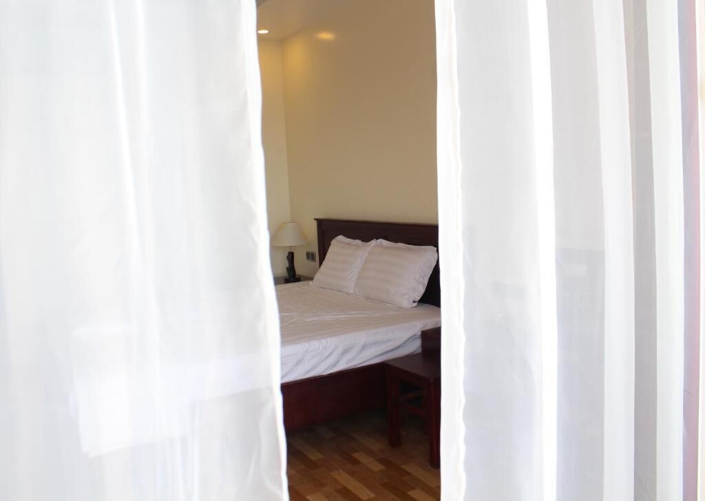 A bedroom with a bed, a nightstand, and a lamp.