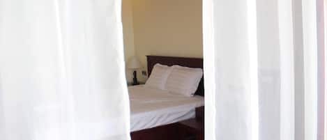 A bedroom with a bed, a nightstand, and a lamp.