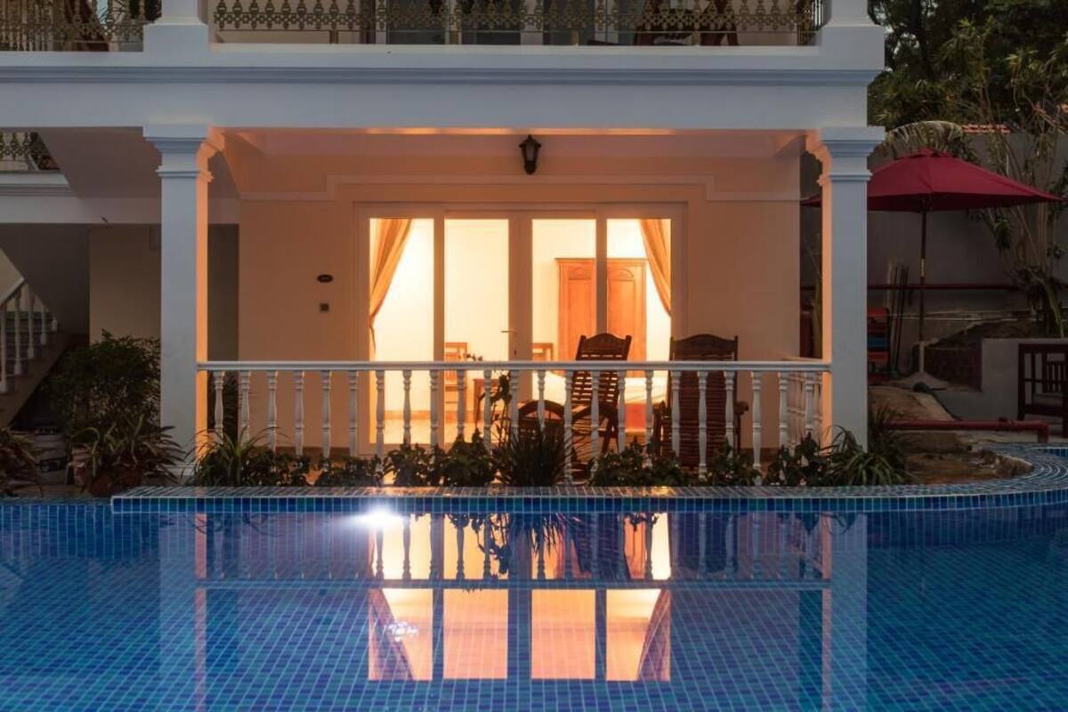 Zona de piscina con un área de estar cubierta, una escalera y vistas a la piscina.