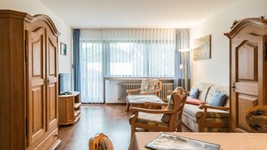 Ein gemütliches Wohnzimmer mit Holzmöbeln, einem Fernseher und einer Heizung.