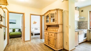 Ein modernes Apartment mit einem Holzschrank, einer Küche mit Herd und einem Schlafzimmer mit Bett und grünem Sofa.