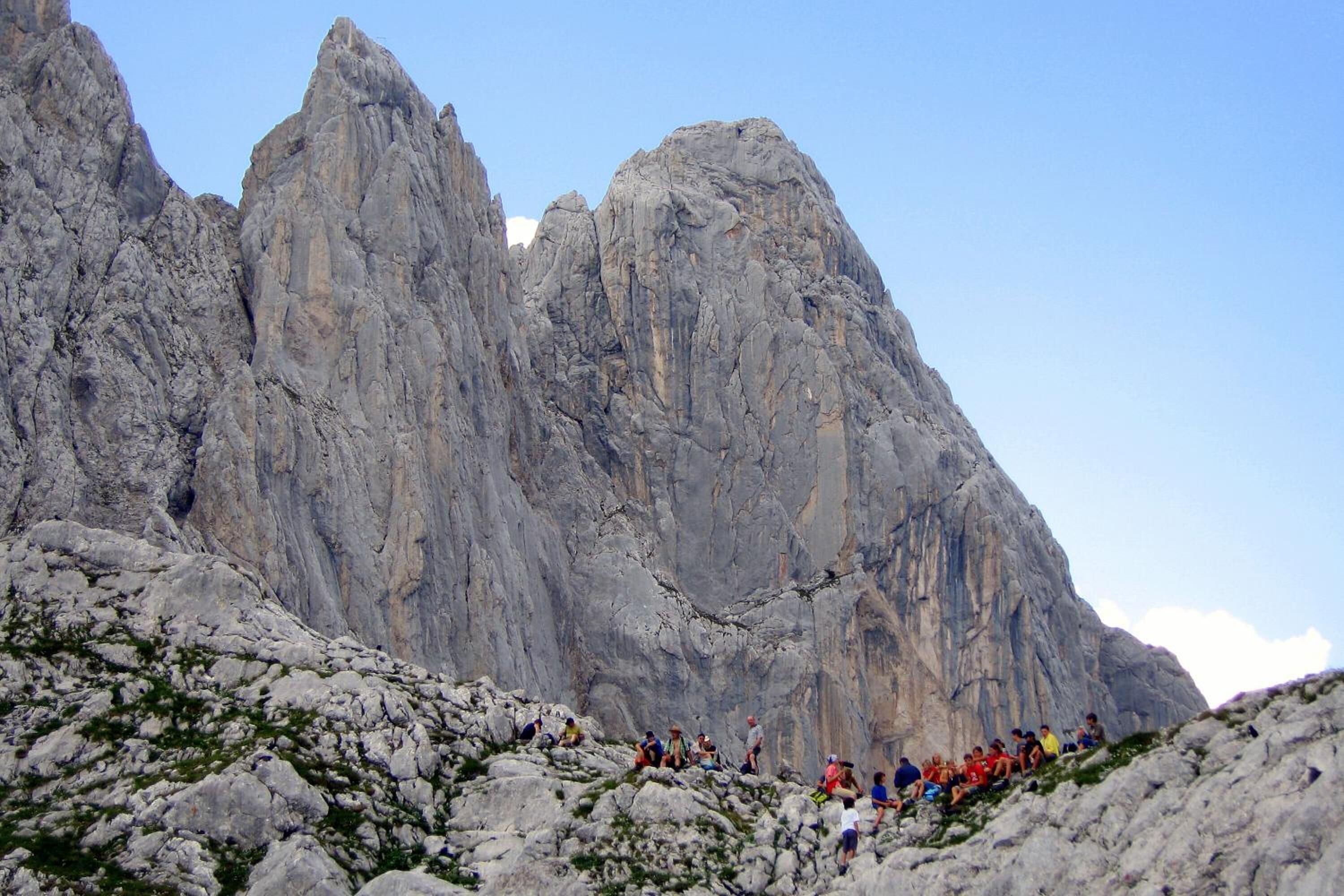 Eine Gruppe Wanderer auf einem felsigen Bergpfad, im Hintergrund steile Klippen.