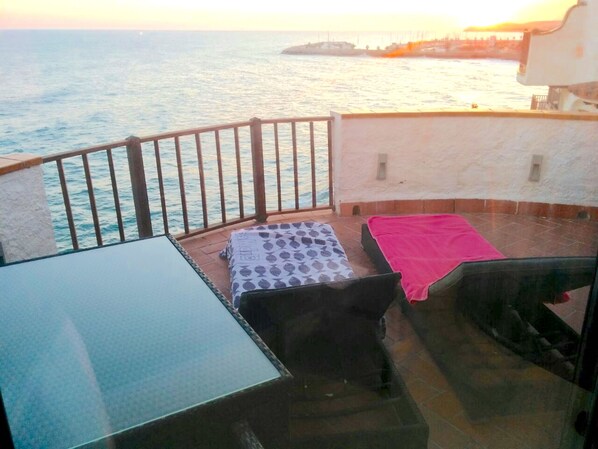 A balcony with a view of the sea, a table, and two beds with blankets. - Sitges. Mediterranean Balcony. Amazing views. Beach and pool. A/C. Parking. WIFI (Sitges)
