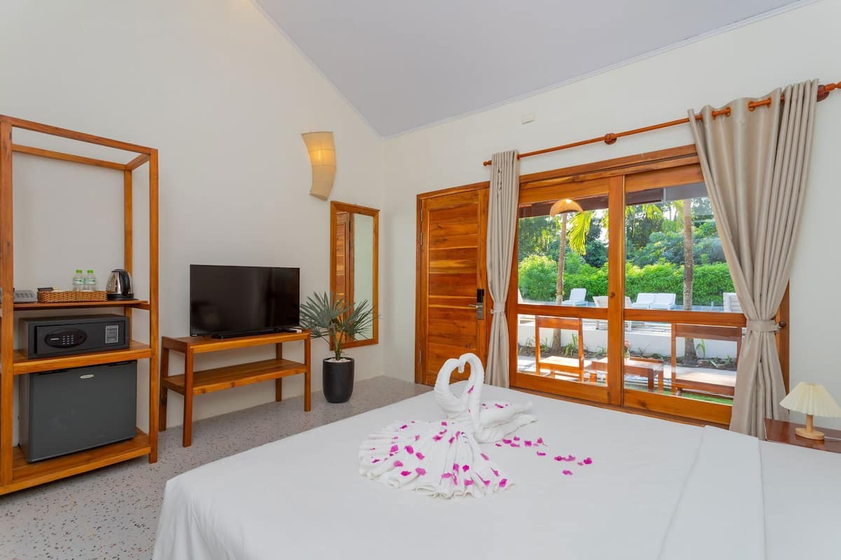 Camera d'albergo con un letto, una TV, un minibar, una pianta in vaso e vista sull'esterno.