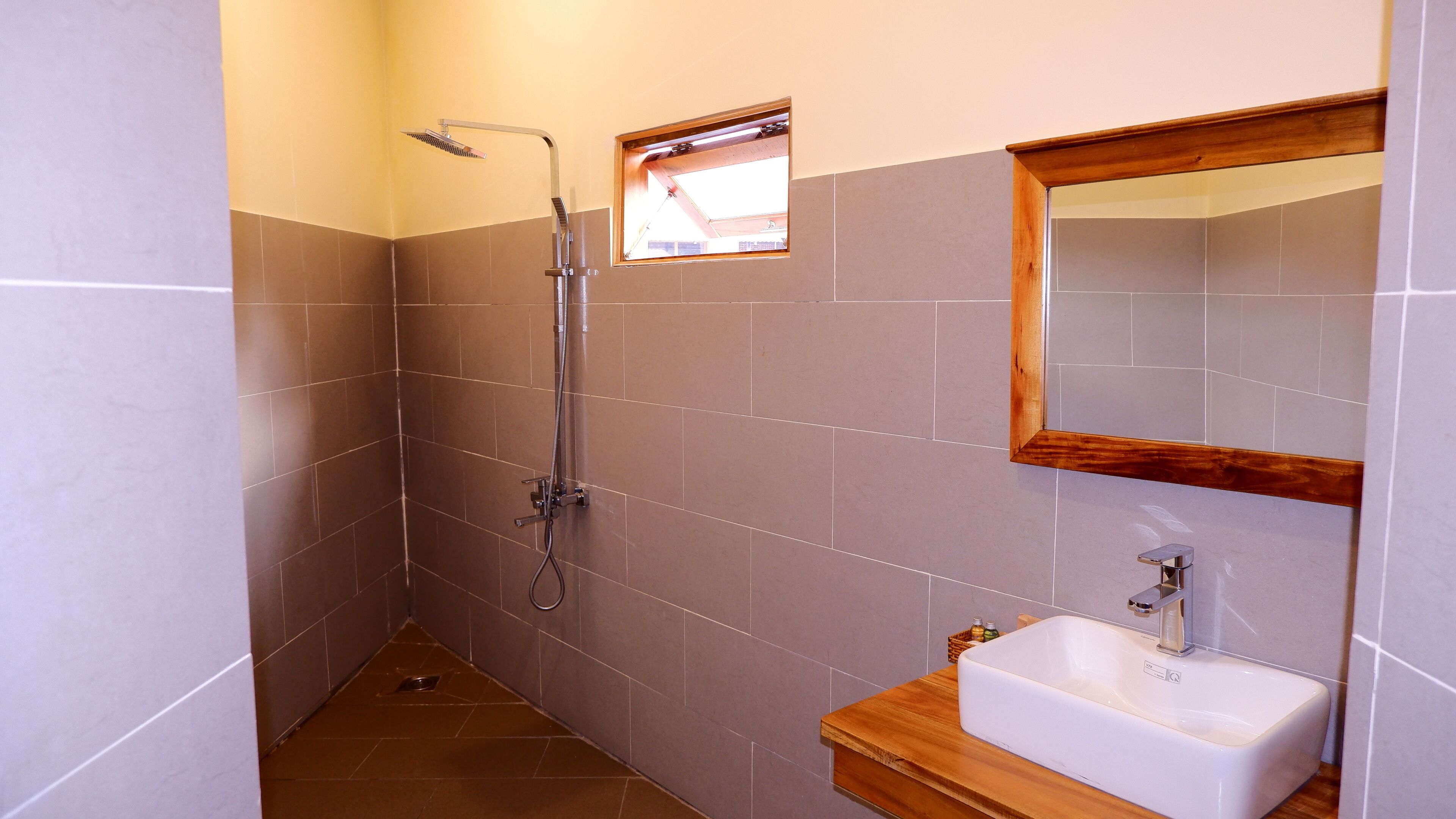 Un baño pequeño y moderno con ducha, lavamanos y espejo.