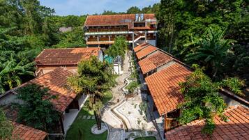 A multi-story building with a tiled roof, surrounded by lush greenery and a winding pathway.